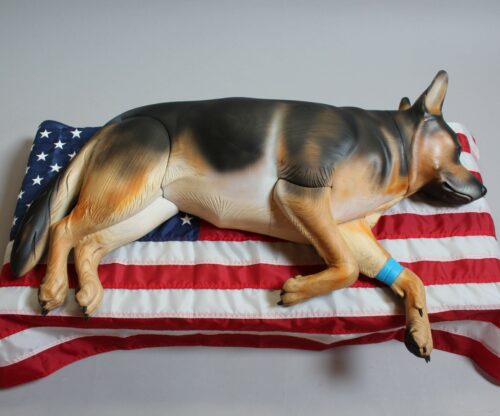 wounded Veteran K-9 carved from wood laying on American flag