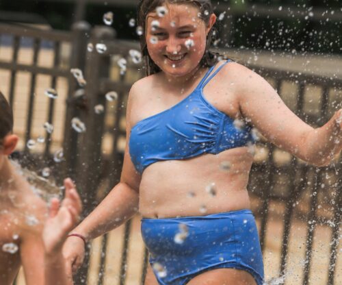 Young girl in blue bathing suite at the splash pad